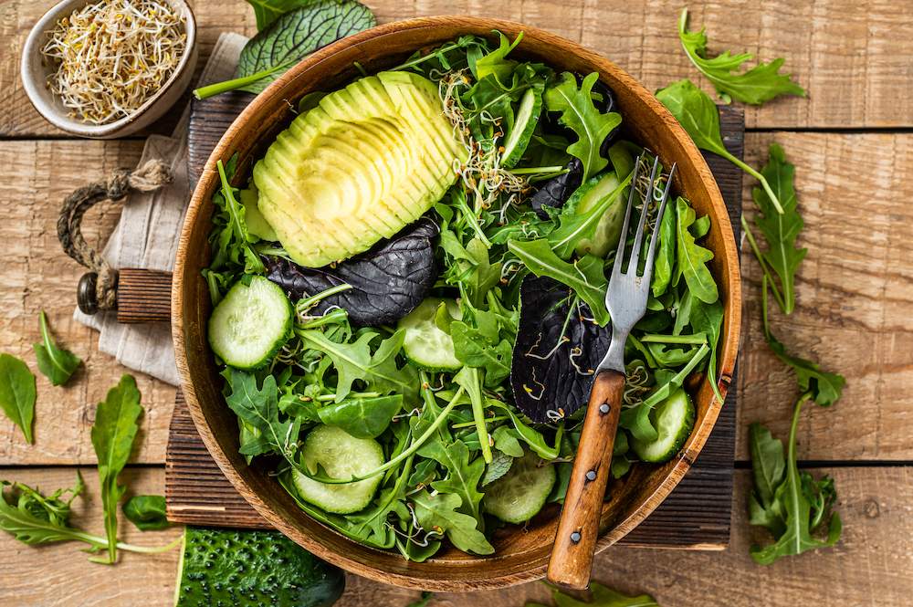Perfect for vegan keto diet: green vegan keto salad with green leaves mix, avocado and vegetables.