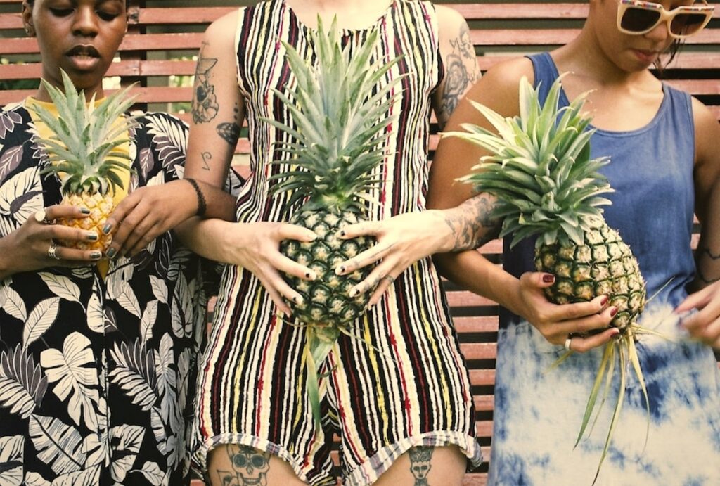 Group of diverse women standing holding pineapple 2022 02 02 03 49 50 utc